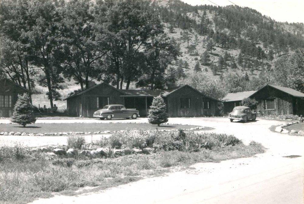 Historic black-and-white photo of rustic cabins and vintage cars at Foot of the Mountain Motel