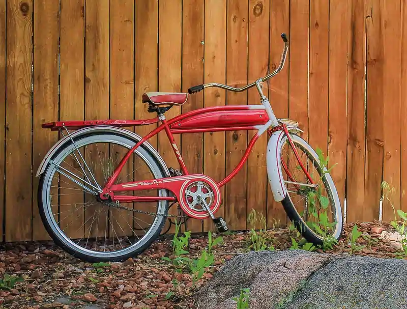 red bicycle on wooden fence
